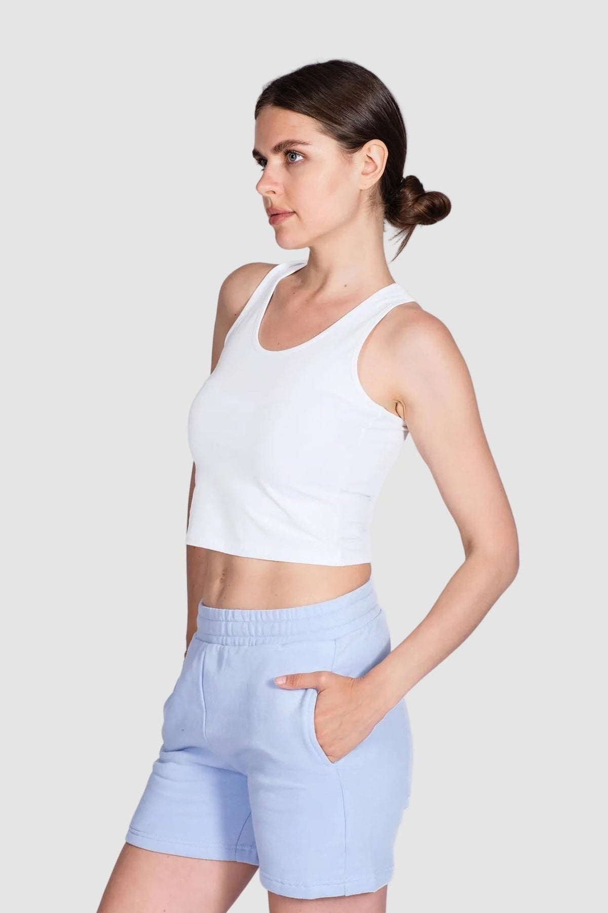 Woman wearing a white tank top and light blue shorts on a white background