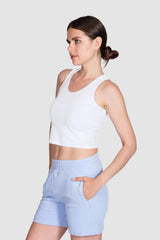 Woman wearing a white tank top and light blue shorts on a white background