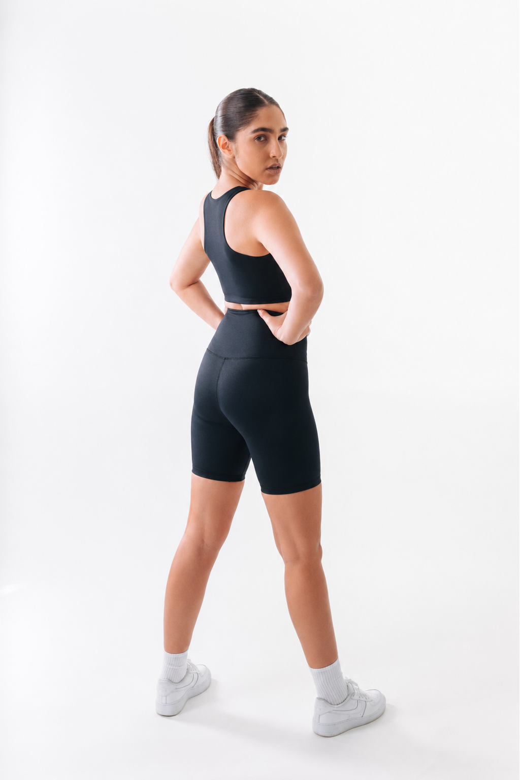 Woman wearing a black athletic outfit on a white background