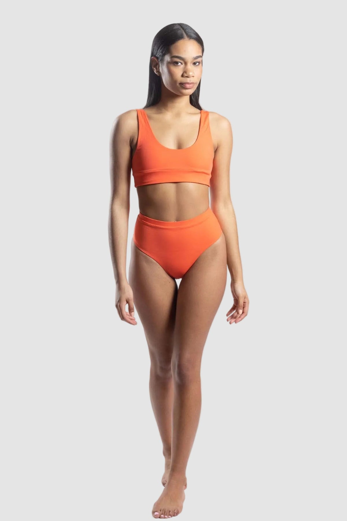 Woman wearing an orange bikini set on a white background