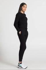 Person wearing a black outfit with white sneakers on a white background