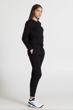 Person wearing a black outfit with white sneakers on a white background