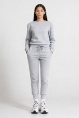 Person wearing a gray sweatshirt and pants set on a white background