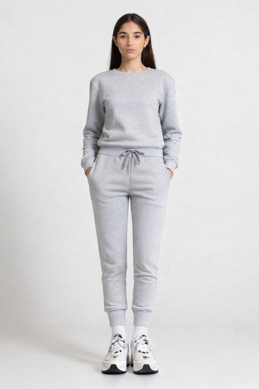 Person wearing a gray sweatshirt and pants set on a white background