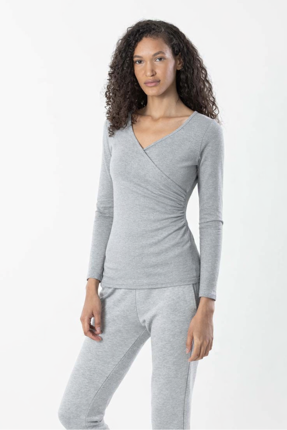 Woman wearing a gray long-sleeve top and pants on a white background
