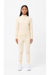 Person wearing a cream-colored tracksuit on a white background