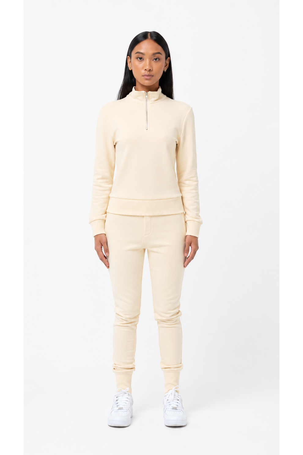 Person wearing a cream-colored tracksuit on a white background