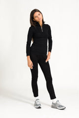 Model in black zip top outfit against a white background.