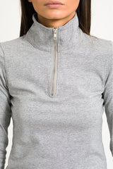 Close up shot of model in half zip top against white background.