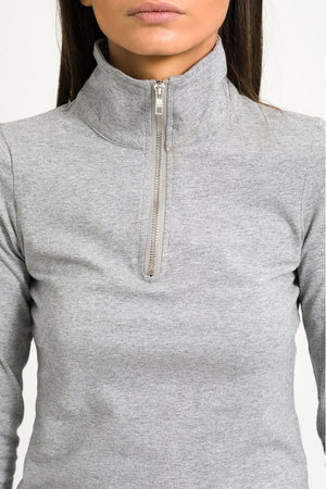 Close up shot of model in half zip top against white background.