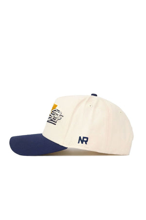 The Montana State Triangle Game Cap Hat features a cream crown, navy brim, and high-quality cotton build. The front has a yellow, black, and white embroidered logo; the side shows "NR" in navy stitching for a structured, stylish fit.
