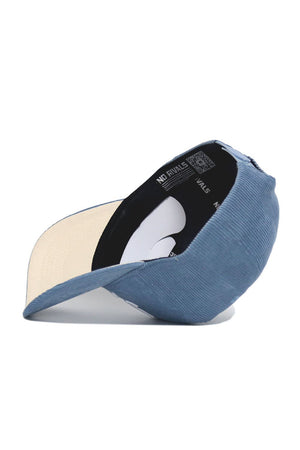 The Iowa Corduroy Hat - Structured - Sky Blue (B2B) by No Rivals is displayed upside down, showing its cream underside brim and a black interior lining with repeated NO RIVALS text.