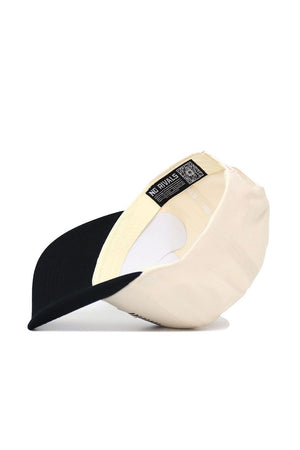 The Iowa Triangle Game Cap Hat by No Rivals is shown upside down, displaying the inner NO RIVALS tag. This cream-colored, structured cotton snapback features a black underside brim and rests on a plain white background.