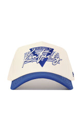 The No Rivals Kentucky Triangle Game Cap Hat is a structured, officially licensed white cap with a blue brim, featuring an embroidered blue "V" and "University of Kentucky" in blue and white on the front.