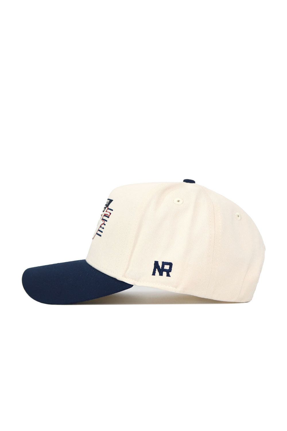 The No Rivals Liberty Triangle Game Cap Hat features a cream-colored snapback design with a navy blue brim, embroidered NR letters on the side, and part of a multicolored design on the front for a stylish, structured fit.