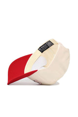 The San Diego State Triangle Game Cap Hat by No Rivals is shown cream-colored, flipped to reveal its red brim, labels—including one with the brand name—structured fit, inner stitching, high-quality cotton, and a visible QR code.