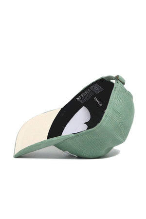 The Dallas Corduroy Hat by No Rivals features an unstructured 6-panel design in spring green with a cream underside and "NO RIVALS" text on the inner lining, shown from the side and slightly underneath.