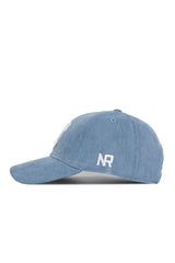 The No Rivals Tennessee Corduroy Hat in Sky Blue features an unstructured 6-panel design, curved brim, white embroidered NR letters on the side, an adjustable strap for a custom fit, and is shown in a left profile view.
