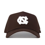 The North Carolina (UNC) Americano Hat (B2B) is a brown snapback with a white interlocking NC logo on the front, made from high-quality cotton and shown on a plain white background.