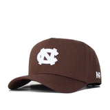 The North Carolina (UNC) Americano Hat (B2B) is a brown snapback featuring a white interlocking NC logo on the front, NF in white on the left side, and is crafted from high-quality cotton for a structured fit.