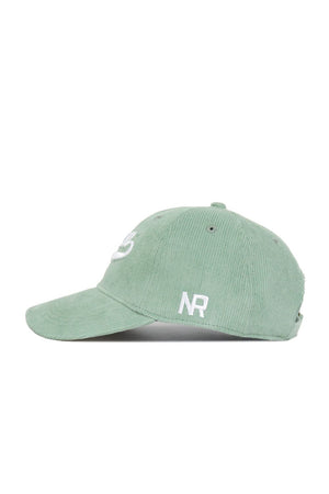 A side view of the No Rivals Iowa Corduroy Hat from the Spring Showers Collection, featuring an unstructured 6-panel design in spring green corduroy, a curved brim, and white embroidered NR initials on the side.