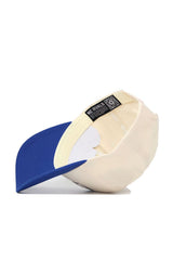 The Memphis Triangle Game Cap Hat by No Rivals features a beige body, blue brim, structured snapback fit, and high quality cotton; shown upside down to display the inside label with NO RIVALS branding and a QR code on the inner band.