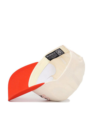 The Sam Houston State Triangle Game Cap Hat by No Rivals is pictured inside out, showing its white sweatband, interior tags, and stitching. This structured snapback features a beige crown, bright red brim, and high-quality cotton construction.