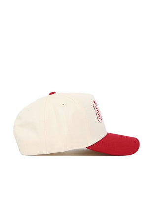 The No Rivals Oklahoma Triangle Game Cap Hat is cream-colored with a red bill and button, shown from the side. The front displays a red and white shield emblem on this officially licensed snapback hat.