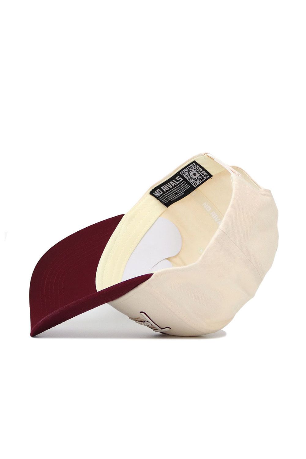 The Texas State Triangle Game Cap Hat by No Rivals is shown upside down, revealing the inside label. The high-quality cotton cap has a dark burgundy brim and a light beige body.