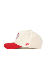 The No Rivals SMU Triangle Game Cap Hat is a cream-colored, structured baseball cap with a red brim, button, and small NR logo, plus embroidered red and blue designs on the front.