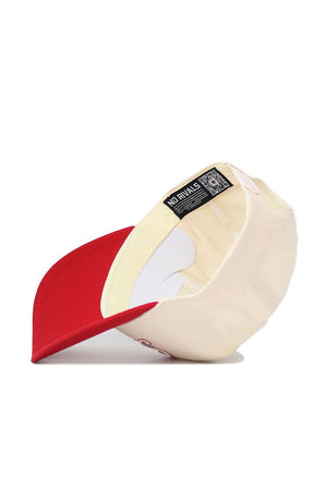 The SMU Triangle Game Cap Hat by No Rivals is shown from below, featuring a cream color with a red brim, structured fit, interior lining, sweatband, and a NO RIVALS label with QR code.