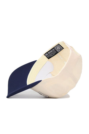 The Penn State Triangle Game Cap Hat by No Rivals is pictured upside down, showing its beige interior, navy blue brim, label with NO RIVALS text, a QR code, and an adjustable snap back strap for a structured fit.