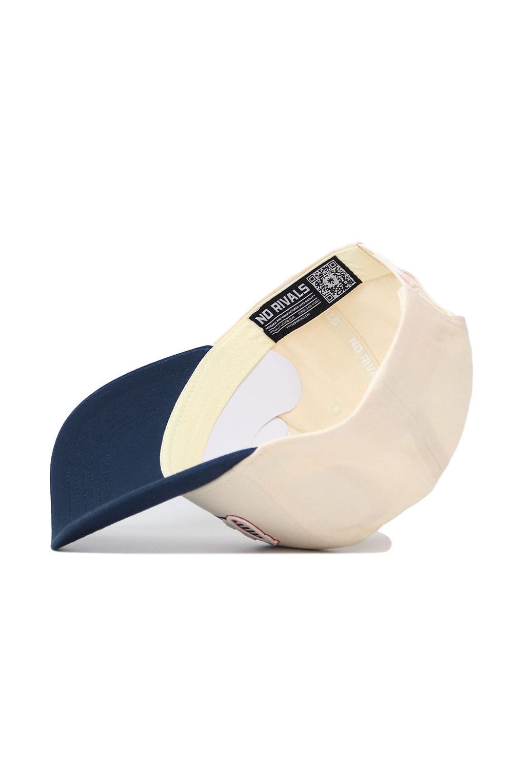 The Ole Miss Triangle Game Cap Hat by No Rivals is shown upside down, revealing its inner label with NO RIVALS and a QR code. It features a navy brim, cream crown, and structured fit for a classic look.