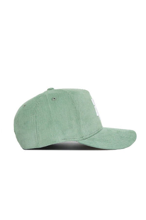 The No Rivals Texas A&M Corduroy Hat in Spring Green features a structured fit, flat brim, and visible stitching on the crown and brim. Shown from the side, this snapback hat offers a fresh look in light green corduroy.