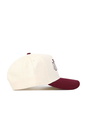 The No Rivals New Mexico State Triangle Game Cap Hat is a cream snapback with a maroon brim and top button, shown from the side. It features a structured fit and a maroon embroidered design on the front panel.