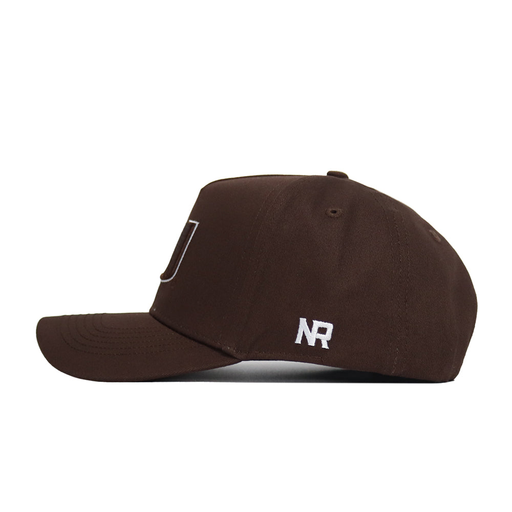 The Miami Hurricanes Americano Hat is a brown structured-fit snapback cap with white 'NR' embroidery near the back, made from high-quality cotton. It features a curved brim and a plain design, shown here in a side view.