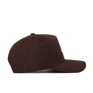The Texas A&M Americano Hat is a brown cotton baseball cap with a curved brim and top button, shown in side profile. It appears plain with no visible logos or designs on the visible side.