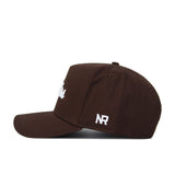 The Ole Miss Americano Hat is a brown high-quality cotton baseball cap with white embroidered "NR" on the side and partially visible white front text, shown from the left side against a white background.