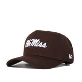 The Ole Miss Americano Hat is a brown cotton cap with "Ole Miss" embroidered in white on the front and "AR" on the side. It features a curved brim, adjustable strap, and is officially licensed.