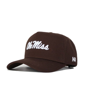 The Ole Miss Americano Hat is a brown cotton cap with "Ole Miss" embroidered in white on the front and "AR" on the side. It features a curved brim, adjustable strap, and is officially licensed.