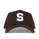 The Syracuse Americano Hat is a brown snapback featuring a bold white “S” embroidered on the front, crafted from high-quality cotton for a structured fit.