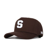 The Syracuse Americano Hat is a brown snapback made from high-quality cotton, featuring a bold white "S" on the front and "NR" on the side, offering a structured fit and lasting style.