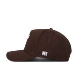 The Tennessee Americano Hat is a dark brown snapback with a curved brim and structured fit. Crafted from high-quality cotton, it features white embroidered NR letters near the back above the brim for lasting comfort and style.