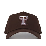 The Texas Tech Americano Hat is a brown, high-quality cotton snapback cap with a large white and maroon Double T logo embroidered on the front. This officially licensed hat is shown against a white background.