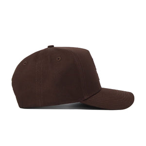 The Texas Tech Americano Hat is shown in a side view on a plain white background. This brown baseball cap features a curved brim and is crafted from high-quality, solid cotton fabric without any adornments.
