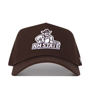 The New Mexico State Americano Hat is a brown snapback baseball cap featuring the NM State logo with a white outline of a cowboy holding pistols and "NM STATE" beneath. Made from high-quality cotton and officially licensed for fans.