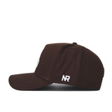 The New Mexico State Americano Hat is a dark brown snapback baseball cap with a flat bill, side view. Made from high-quality cotton, it features white embroidered NR letters on the back panel.