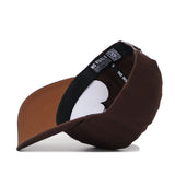 The New Mexico State Americano Hat is a brown snapback baseball cap made from high quality cotton, shown angled with the brim left. It features a black inner band with NO RIVALS text and a QR code.