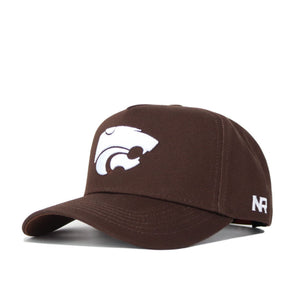 The Kansas State Americano Hat is a brown cotton baseball cap with a white wildcat logo on the front and white NR lettering on the side, displayed against a plain background.