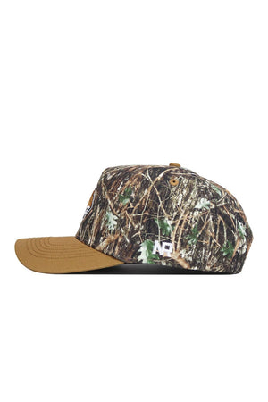 The Montana State Camo Hat - Explorer Edition is a structured-fit, high-quality cotton baseball cap featuring a brown brim, green-brown-tan camo design, and a white AP logo embroidered on the side. The image displays the cap's side profile.